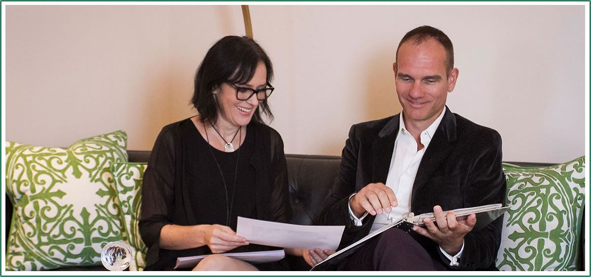 Lisa Clampitt seated on the office sofa, smiling as she reviews paperwork with a client during a consultation